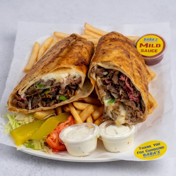 Two Baba's shawarma wraps, fries, salad, and sauces on a white plate.