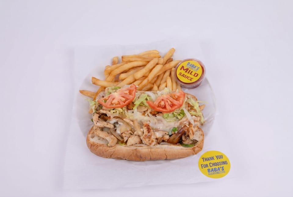 Chicken sub sandwich with lettuce, tomatoes, and fries, with Baba's Mild Sauce.