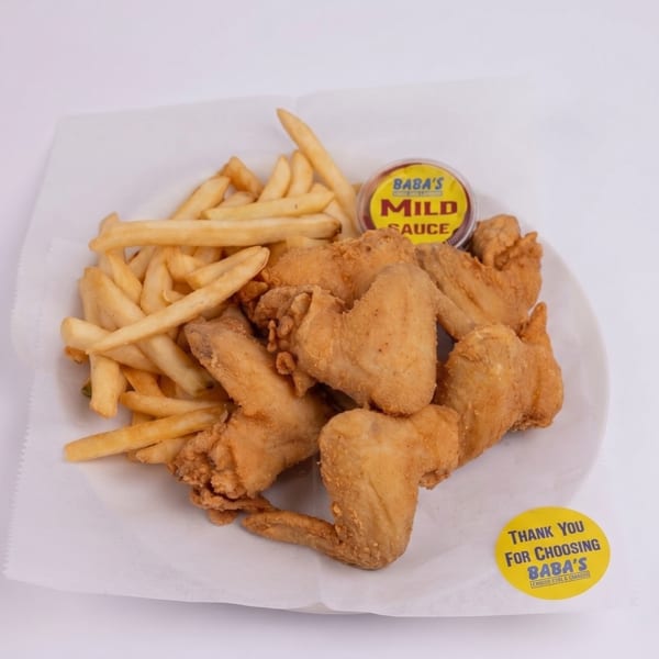 Baba's fried chicken wings and french fries with a side of mild sauce on a white plate.