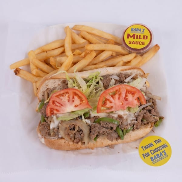 Cheesesteak sandwich with lettuce, tomatoes, onions, and peppers, served with fries and Baba's Mild Sauce.
