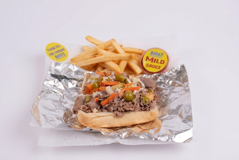 Baba's Italian beef sandwich with giardiniera, fries, and mild sauce on foil.